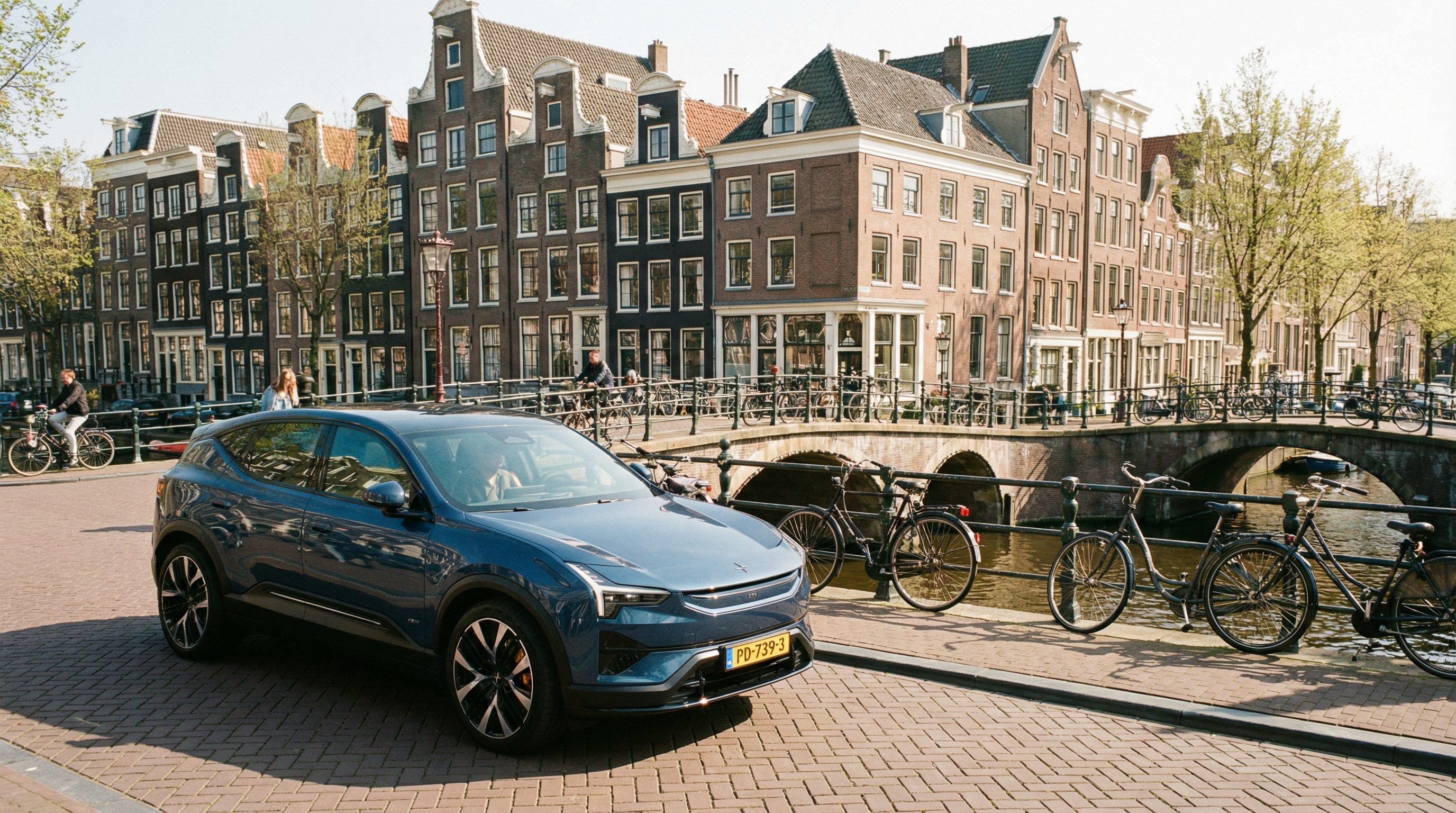 Dica: Um carro elétrico moderno e impecável estacionado ao longo de um pitoresco canal holandês, com bicicletas ao fundo